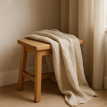 Compact oak stool in a small corner with linen throw
